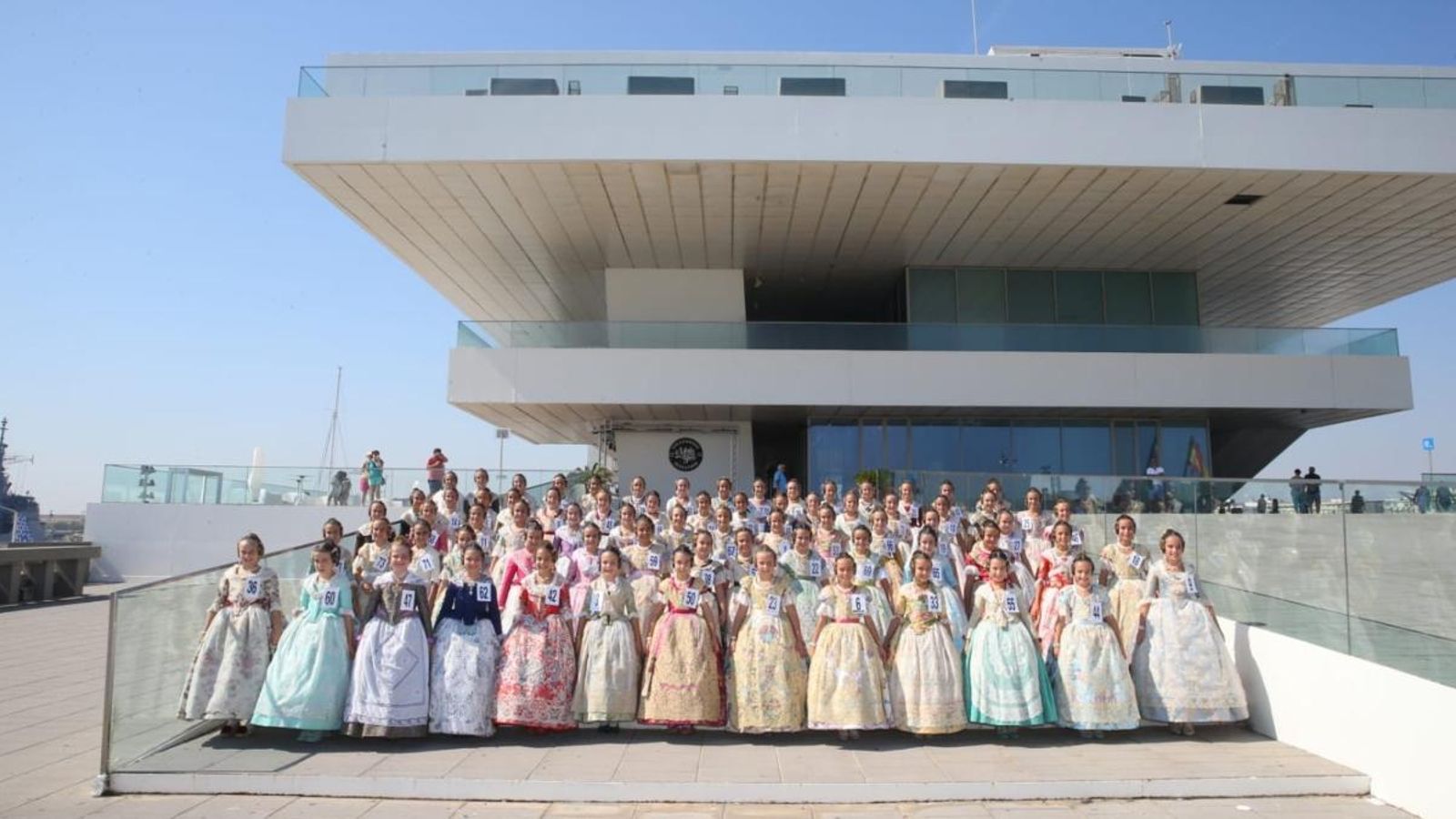 Les candidates a Fallera Major Infantil de València vestides de valencianes davant l'edifici Veles e Vents