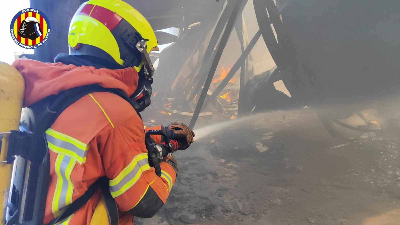 La nau, completament calcinada, mentre els efectius de bombers treballen en l'extinció