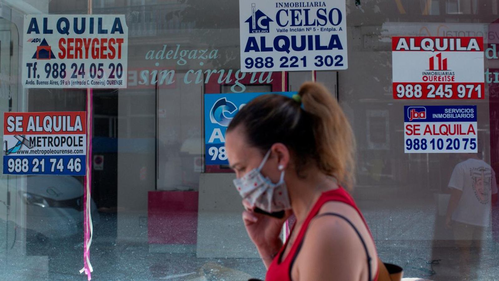 Una dona amb mascareta passa per davant d’un comerç tancat