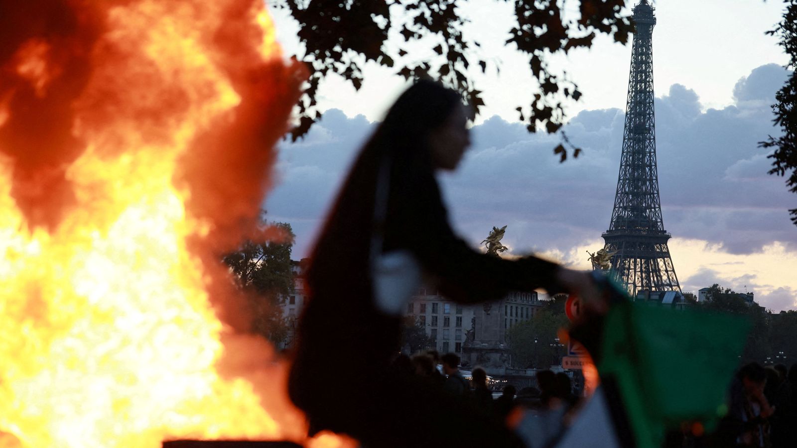 Una ciclista passa al costat d'una barricada en flames, amb la Torre Eiffel de fons, a París, el passat cap de setmana