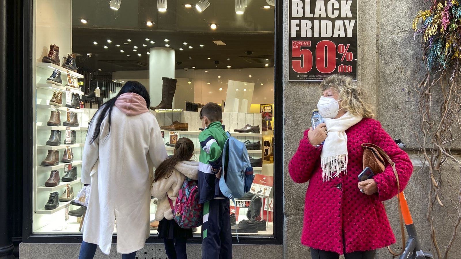 Diverses persones miren un aparador que anuncia descomptes del 50% pel Black Friday