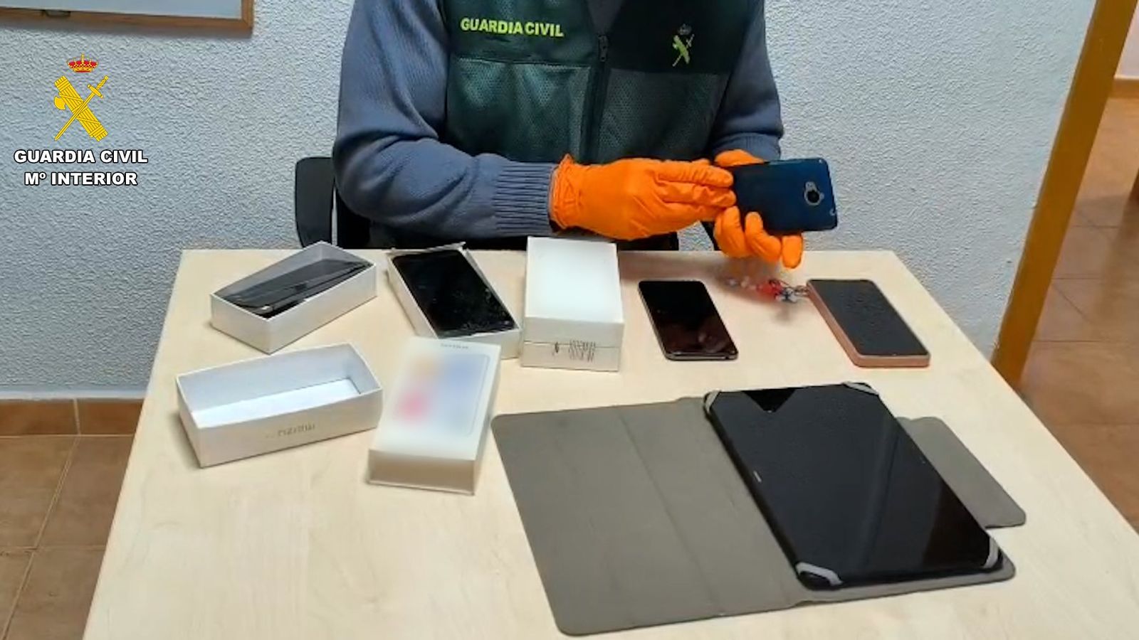 Un agent revisa diversos dispositius electrònics incautats a la parella detinguda