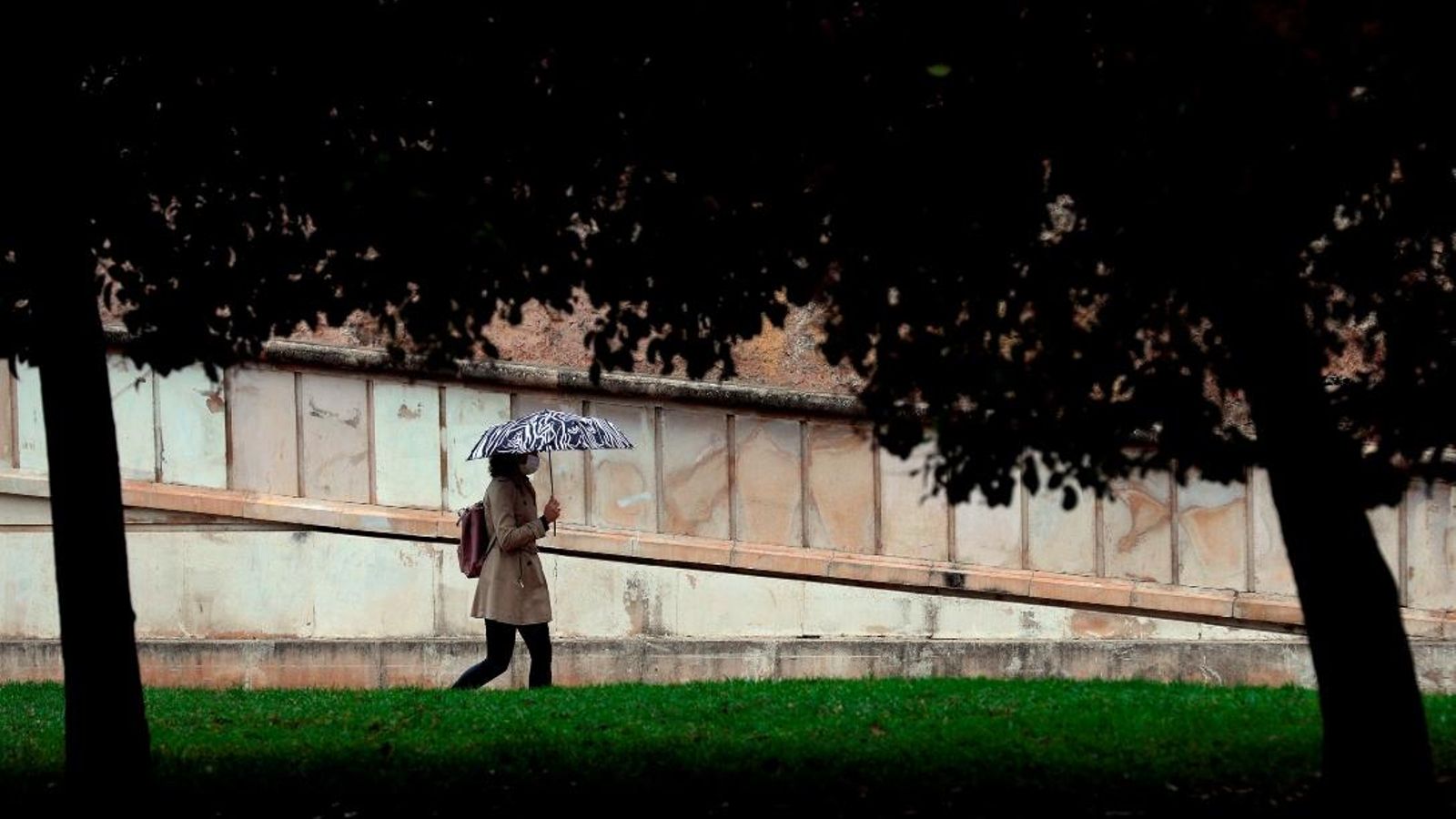 Una dona es protegeix de la pluja a València