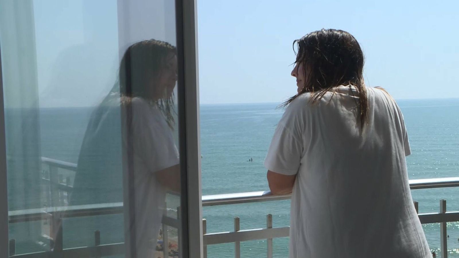 Una xica s'asoma al balcó davant de la mar