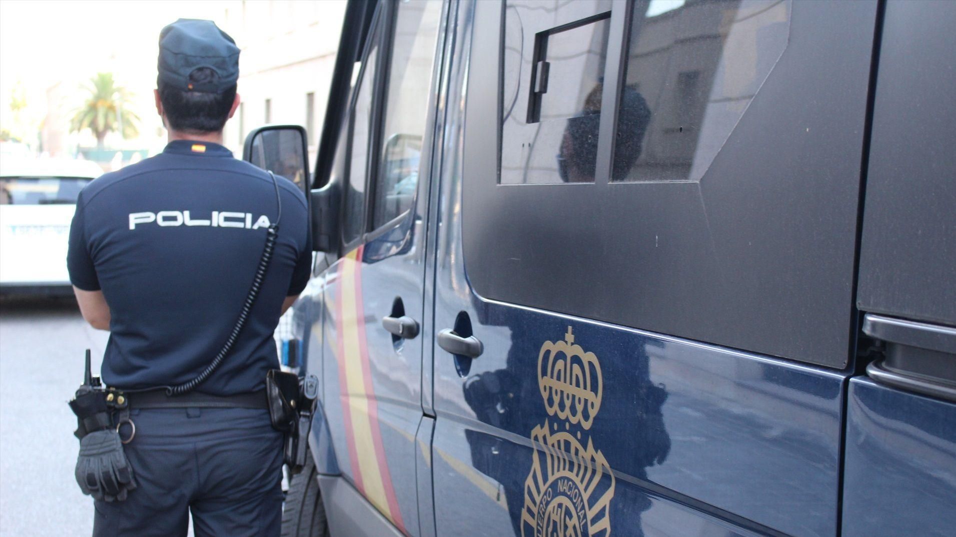 Agent de la Policia Nacional al costat d'un furgó policial a València Presó provisional per a un home per agredir un sense sostre