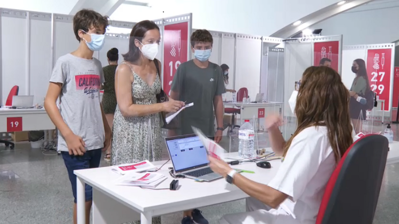 Dos germans menors de dotze anys, acompanyats per sa mare, a un punt de vacunació