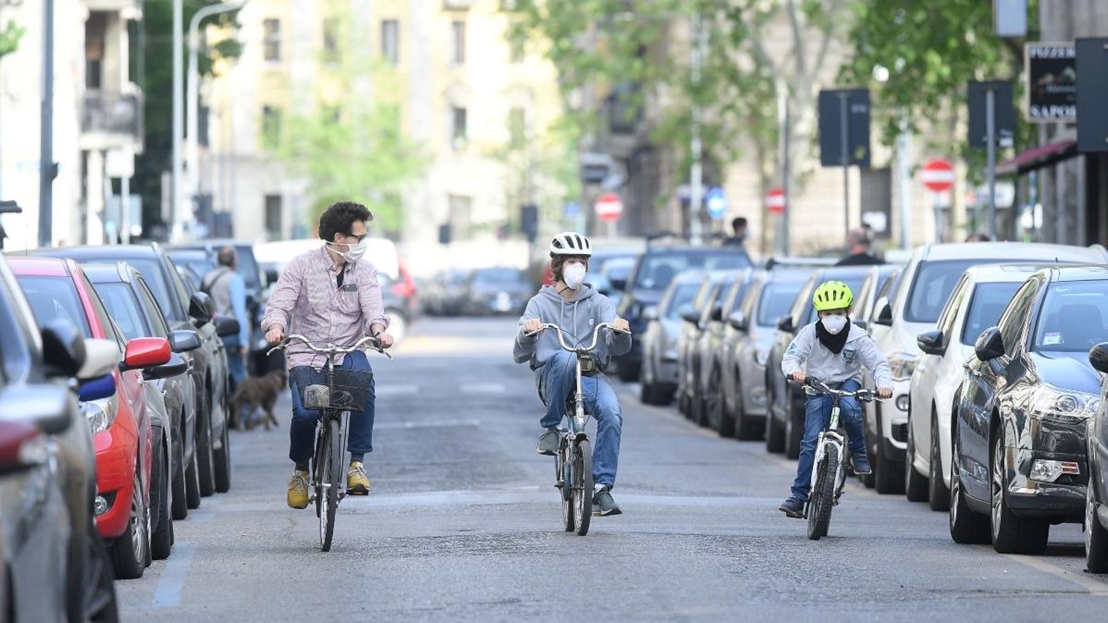 Un pare circula amb els fills en bicicleta pels carrers de Milà