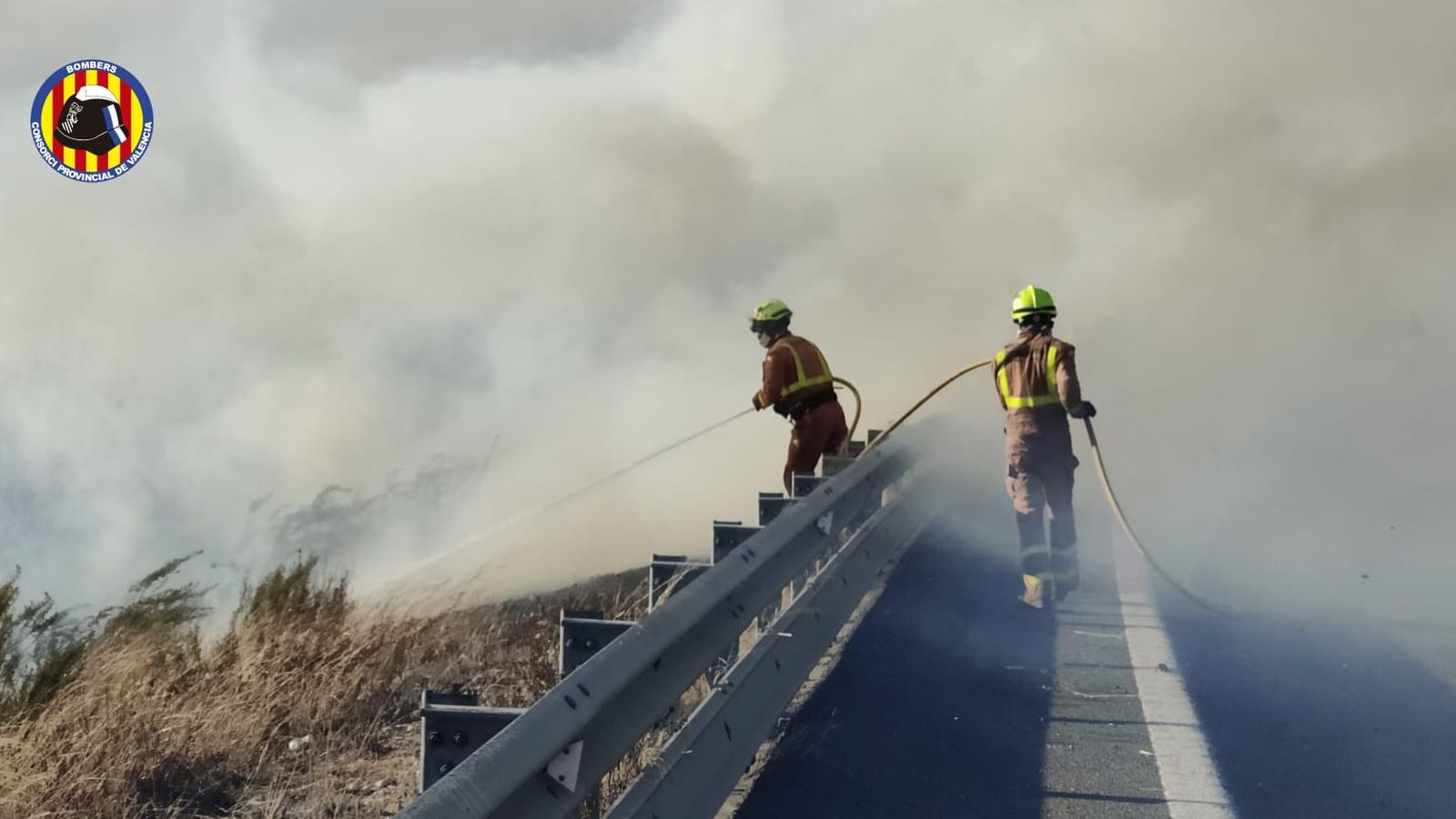 Bombers treballant en les tasques d'extinció de l'incendi prop de l'A-38