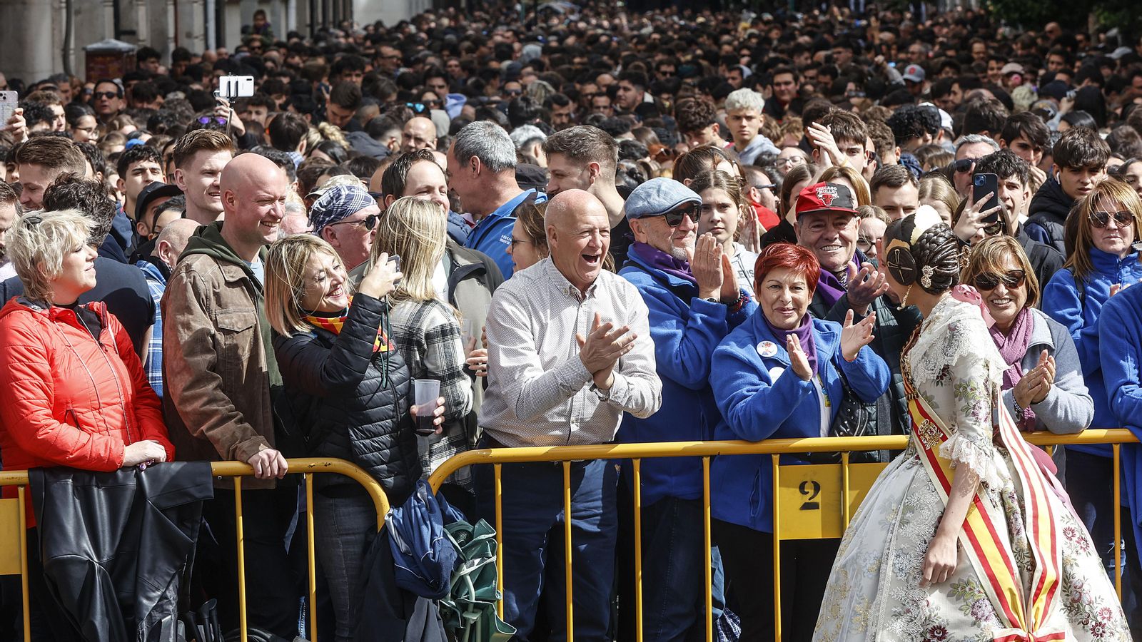 Una fallera saluda durante una mascletà de las Falles 2024