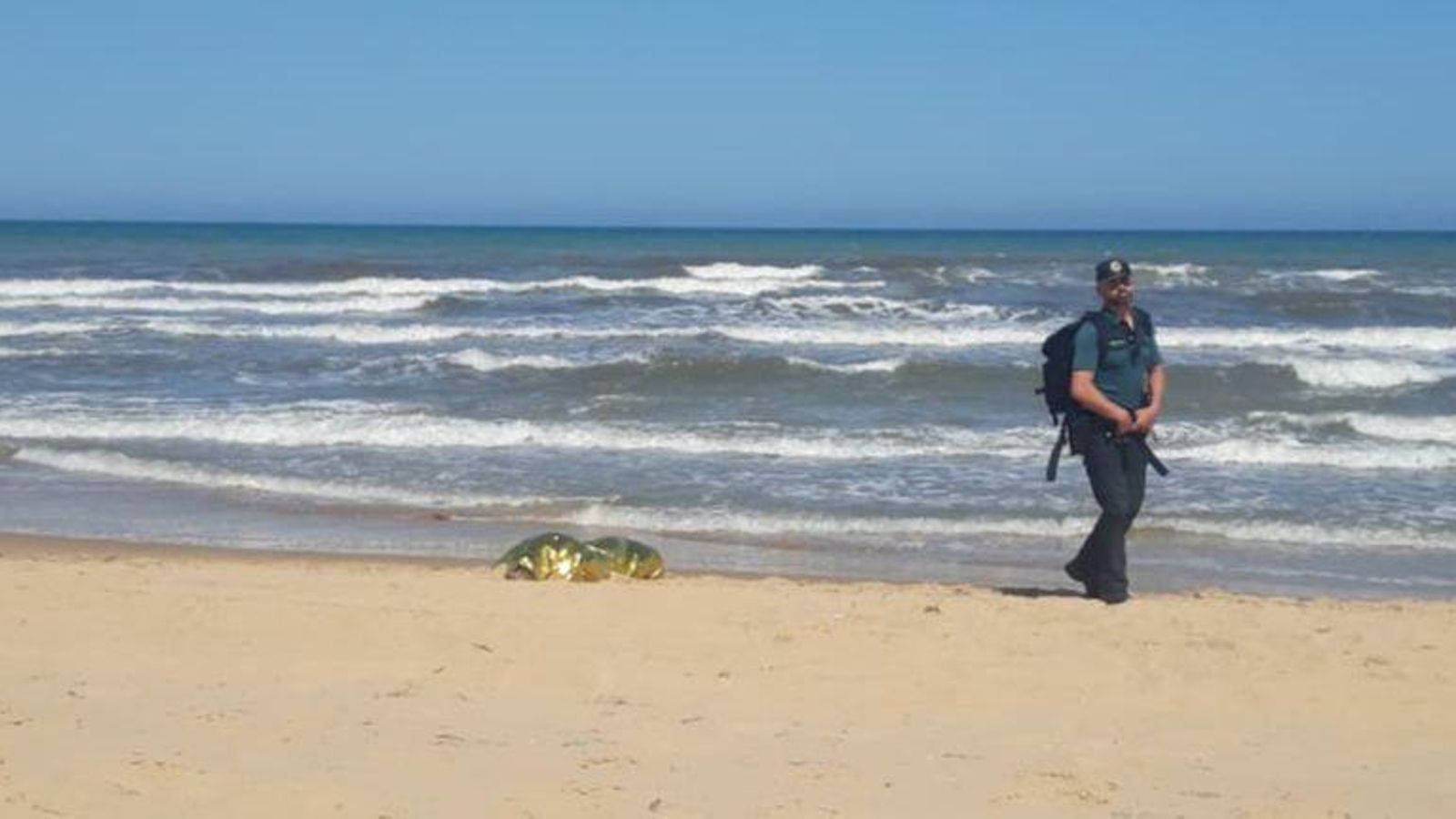 Un agent de la Guàrdia Civil passa al costat del cos sense vida de l'home ofegat aquest dissabte a Guardamar del Segura