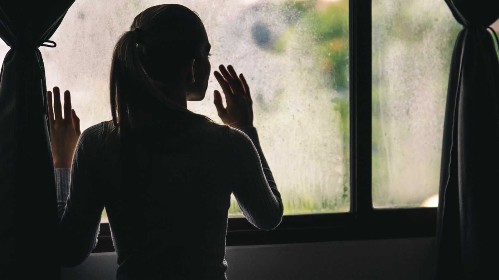 Una dona confinada a casa mira per la finestra