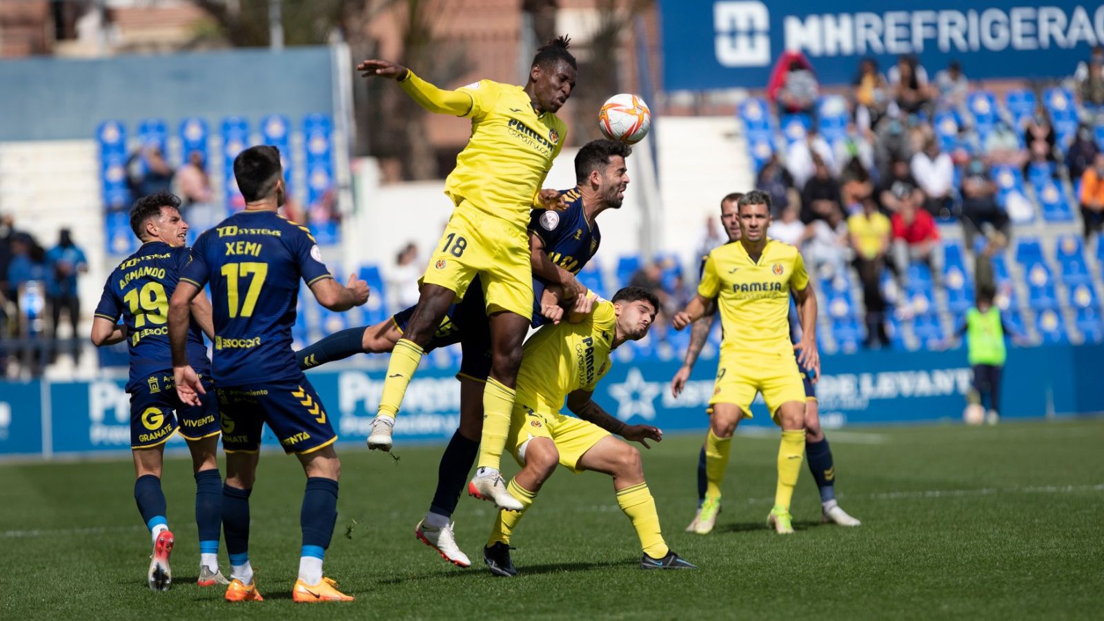 Dos jugadors del Vila-real B i un del Múrcia disputen una pilota aèria