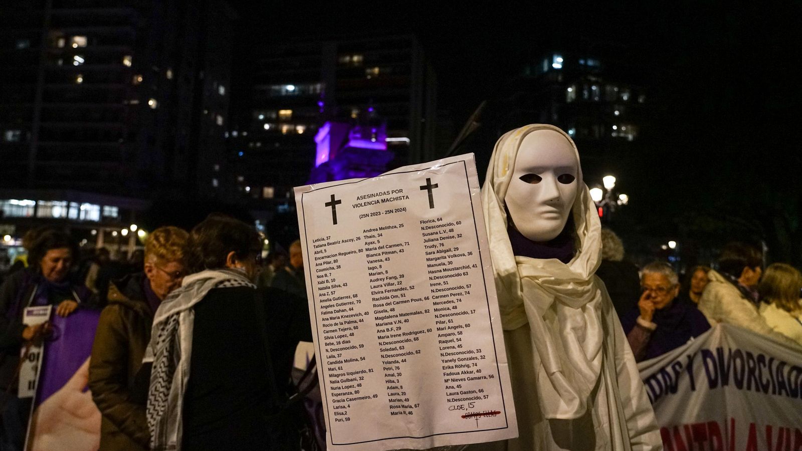 Una persona sosté un cartell amb les víctimes de violència de gènere a Espanya, durant la manifestació del 25N