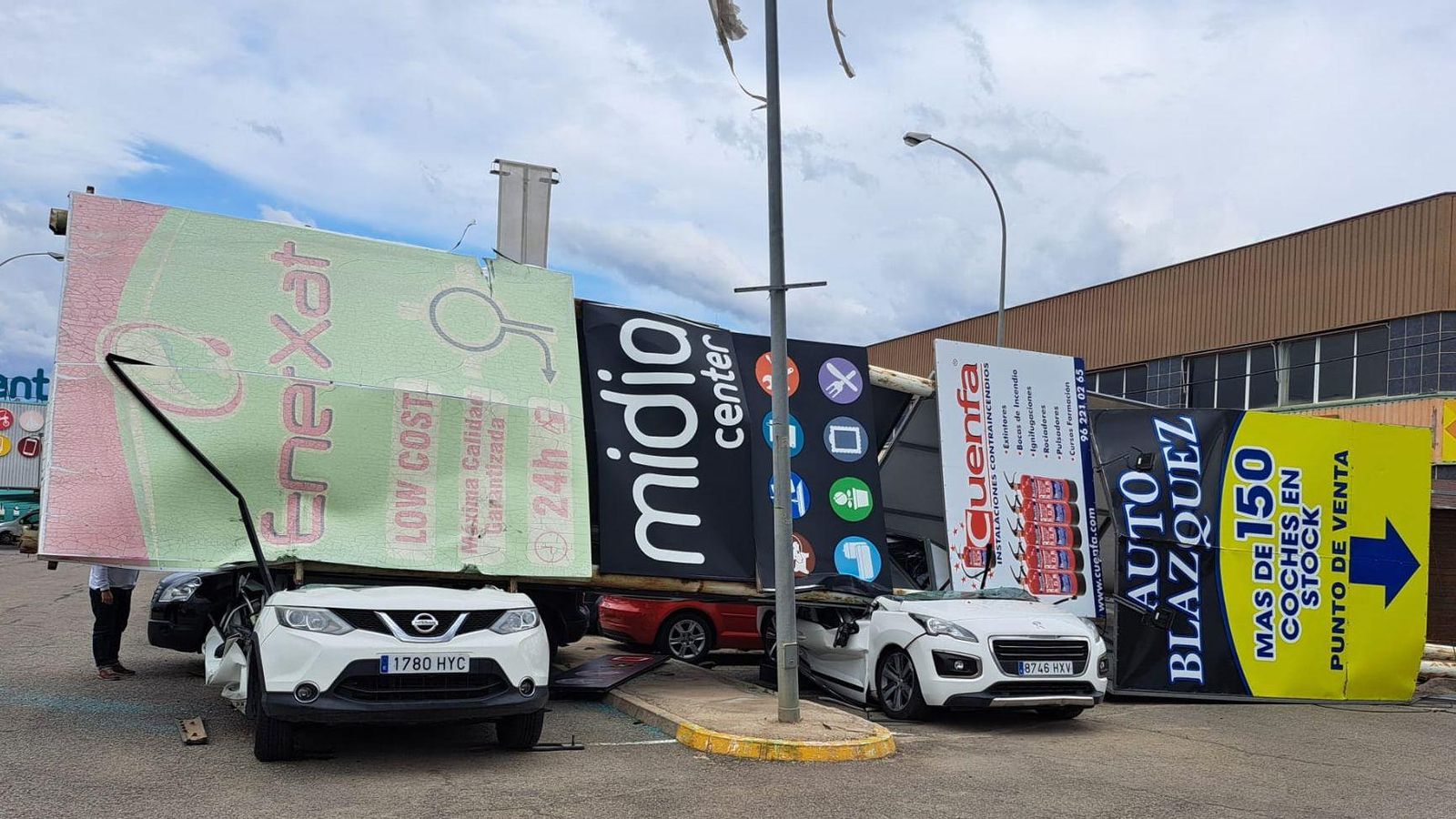 Una tanca publicitària ha caigut per culpa del vent sobre aquests dos cotxes
