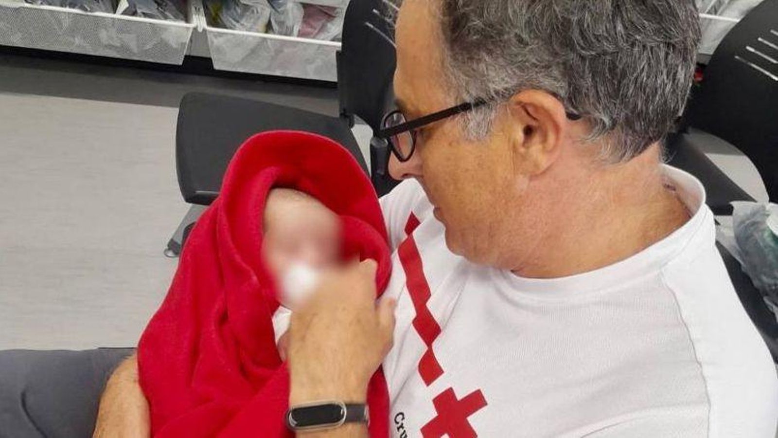 Un voluntari de la Creu Roja agafa el bebé que anava en la pastera