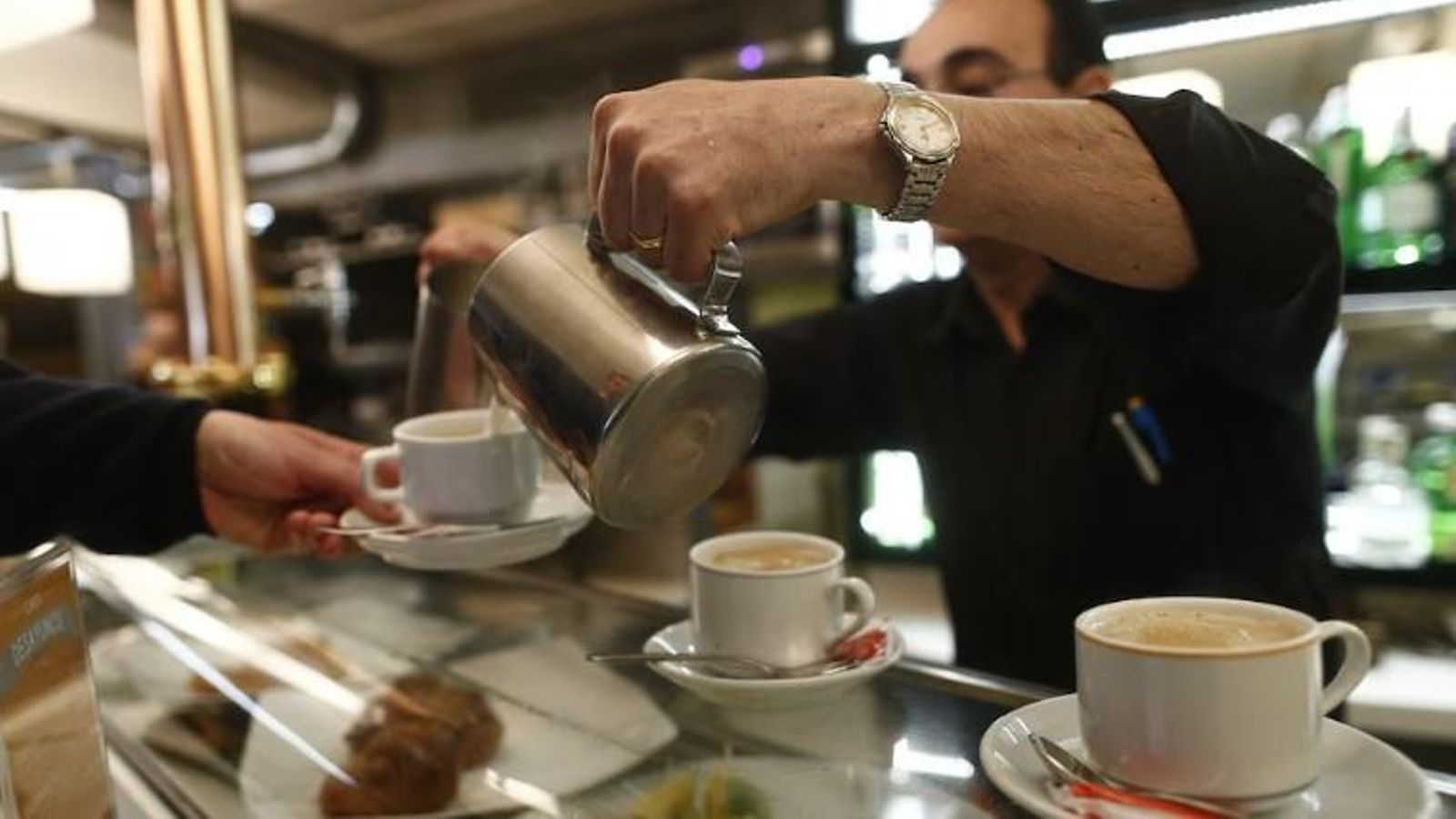 Un cambrer serveix una tassa de café