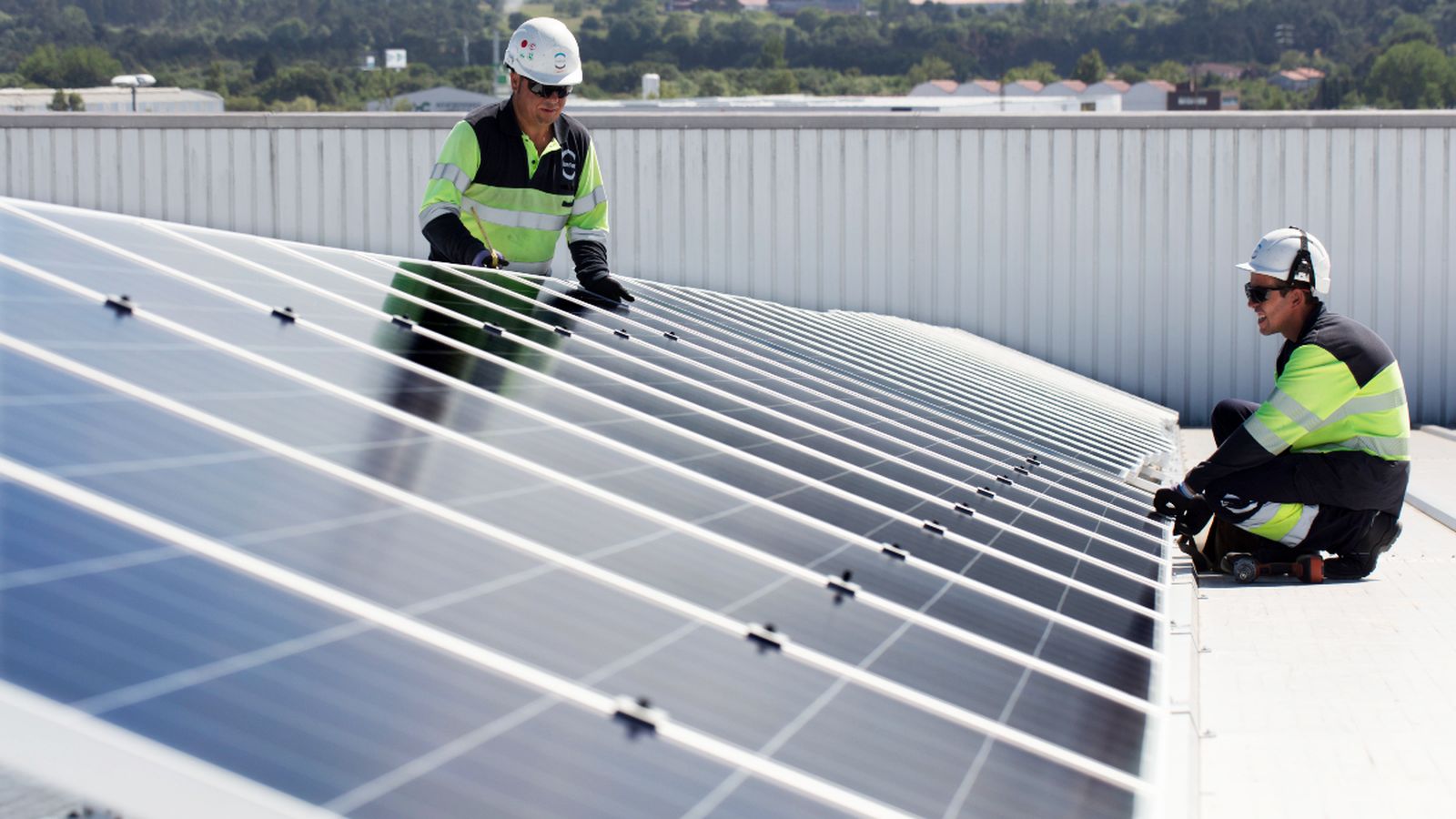 Dos operaris col·loquen un panel en una instal·lació fotovoltaica