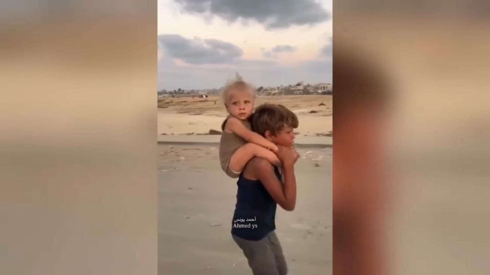 Un xiquet desplaçat del nord de Gaza porta la seua germana a l'esquena