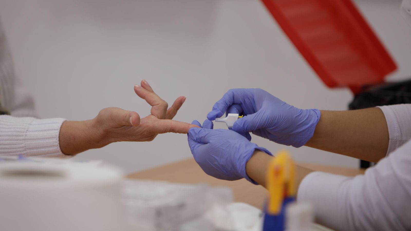 Personal sanitari de Creu Roja trau sang d'un dit a una persona per a realitzar el test ràpid de detecció d'anticossos