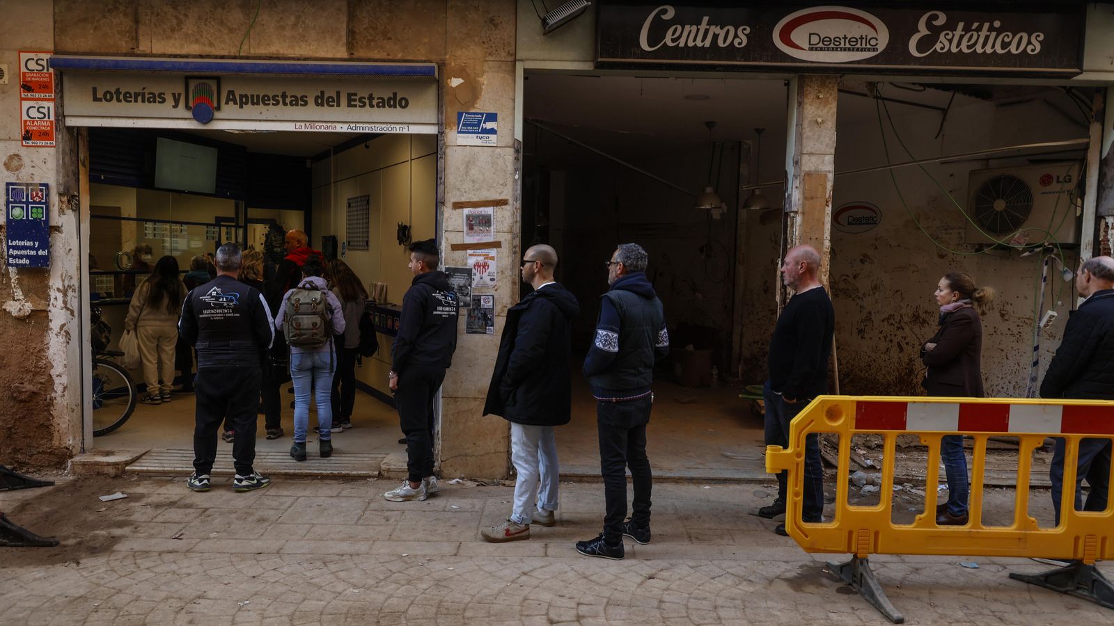 Diverses persones fan cua en una administració de loteria de Paiporta després de la DANA