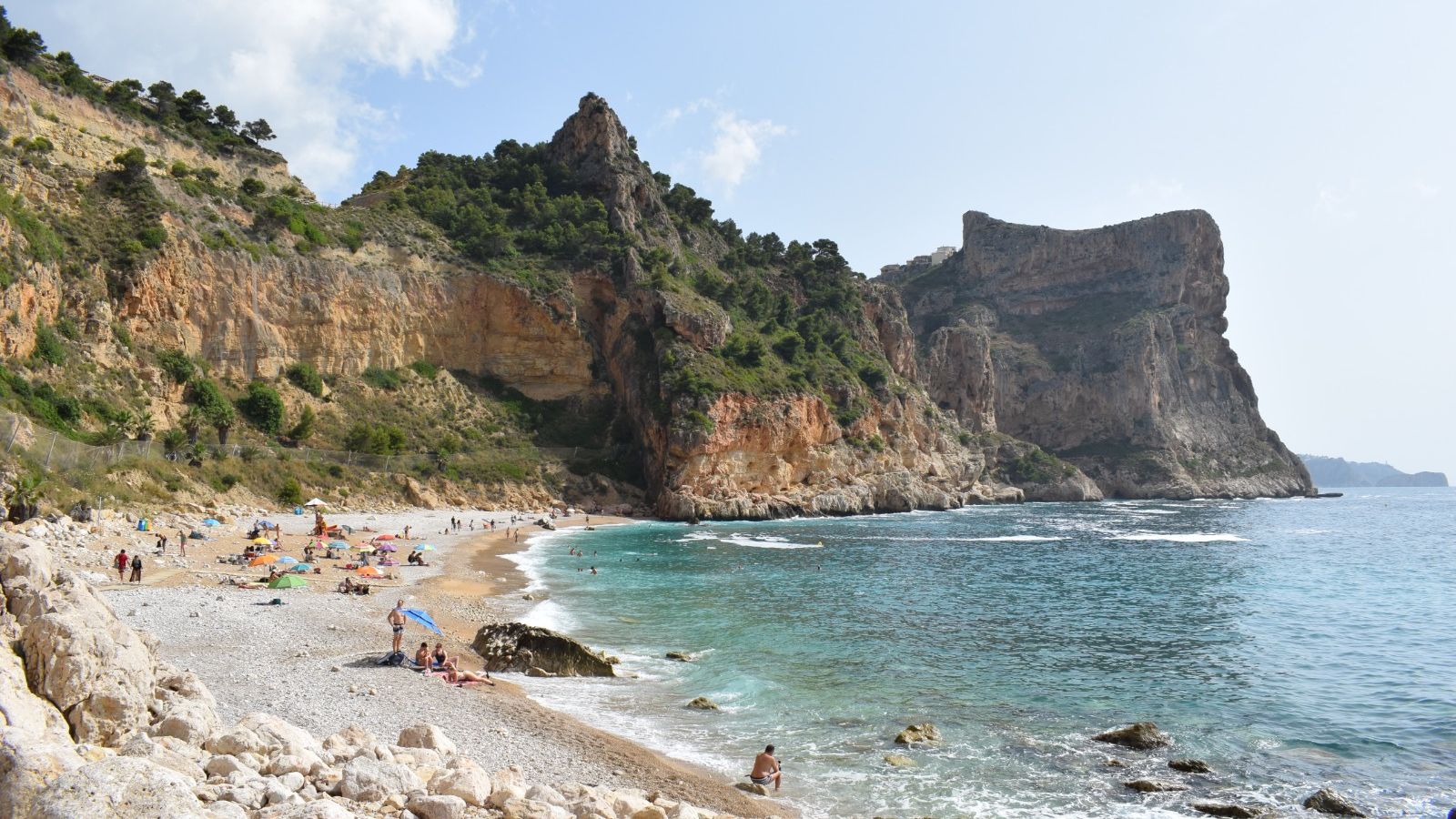 Banyistes gaudeixen d'un dia de platja a la cala Moraig