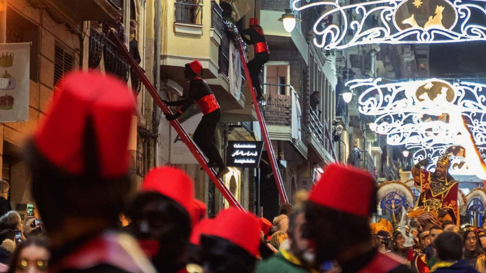 Els patges pugen fins a les cases dels més menuts carregats de regals i amb ajuda d'unes escales roges