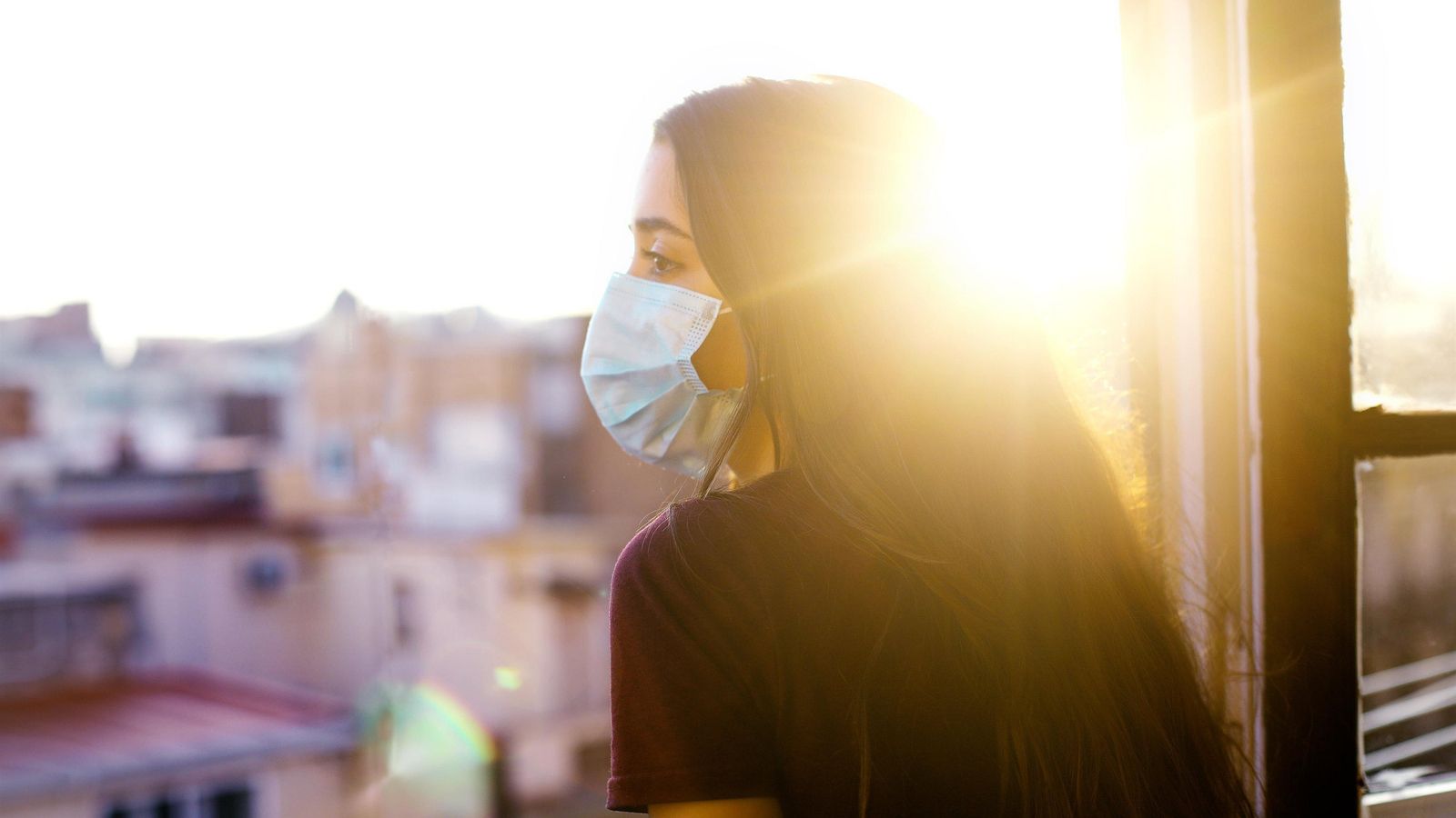 Una jove mira per la finestra d'una casa (arxiu)