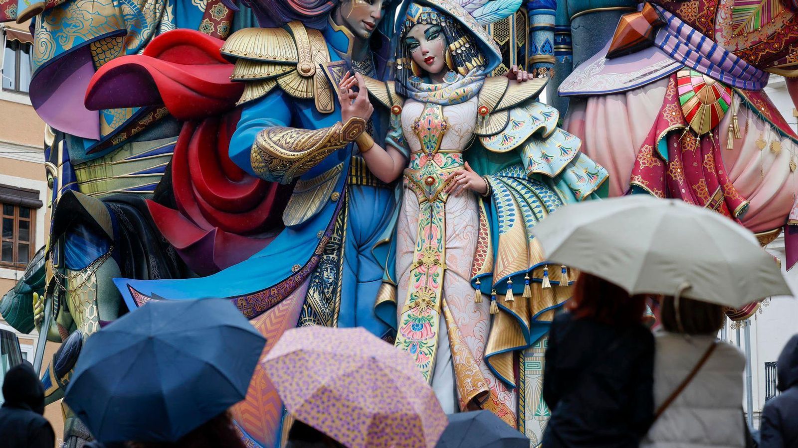 Diverses persones cobertes amb paraigua contemplen el monument de la Falla Convent de Jerusalem