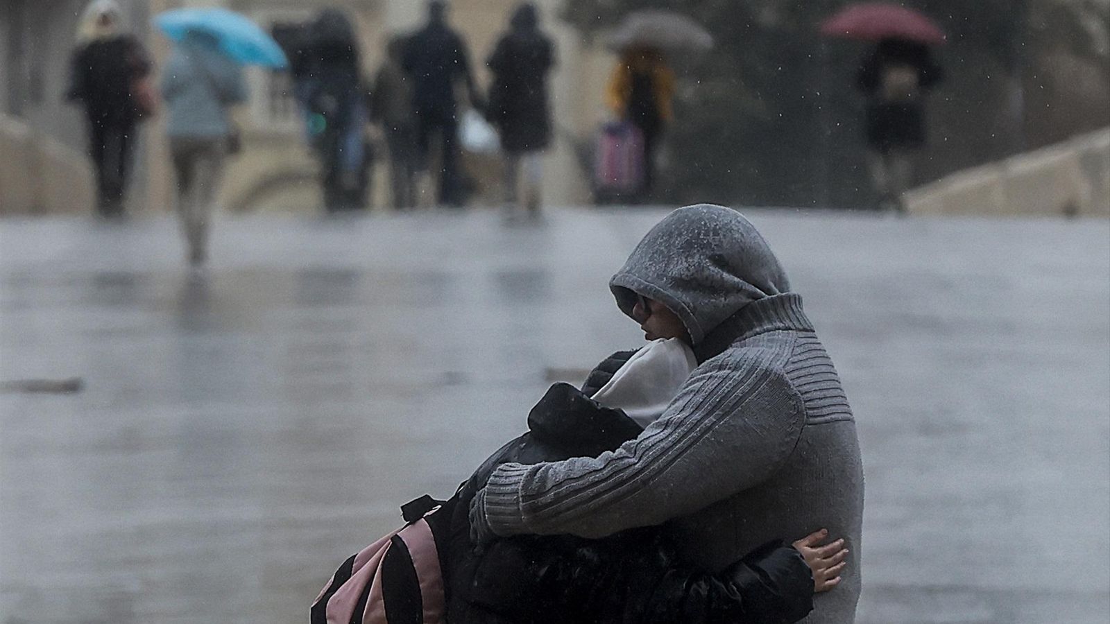Una parella s'baraça sota la pluja en una imtge d'arxiu