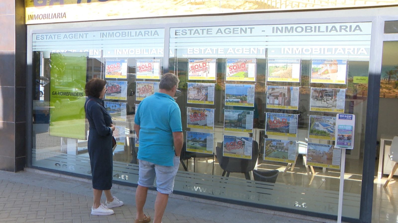 Dos persones observen un mostrador d'una immobiliària