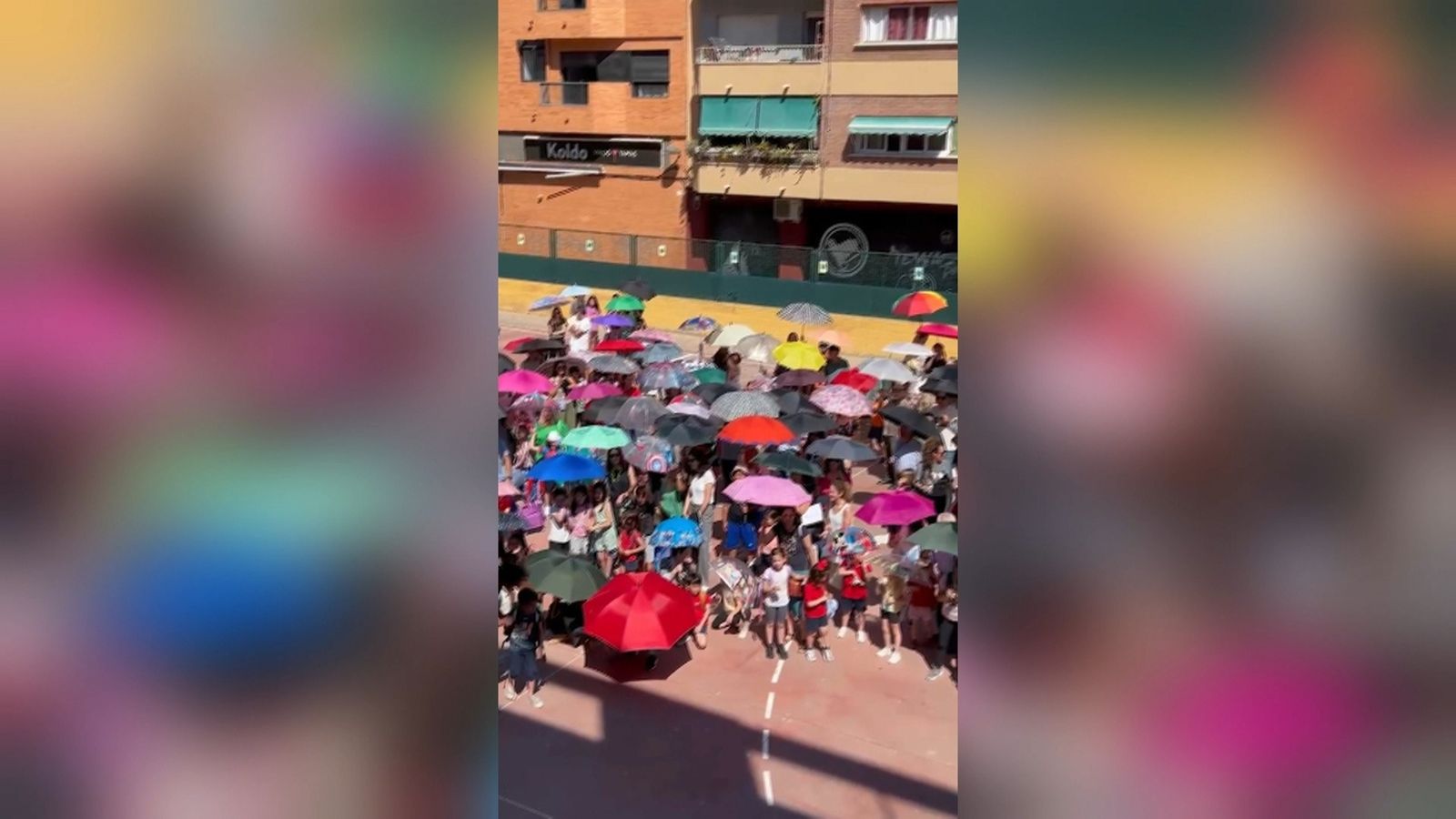 Alumnat al pati del CEIP Mestalla de València protegint-se del sol amb paraigua