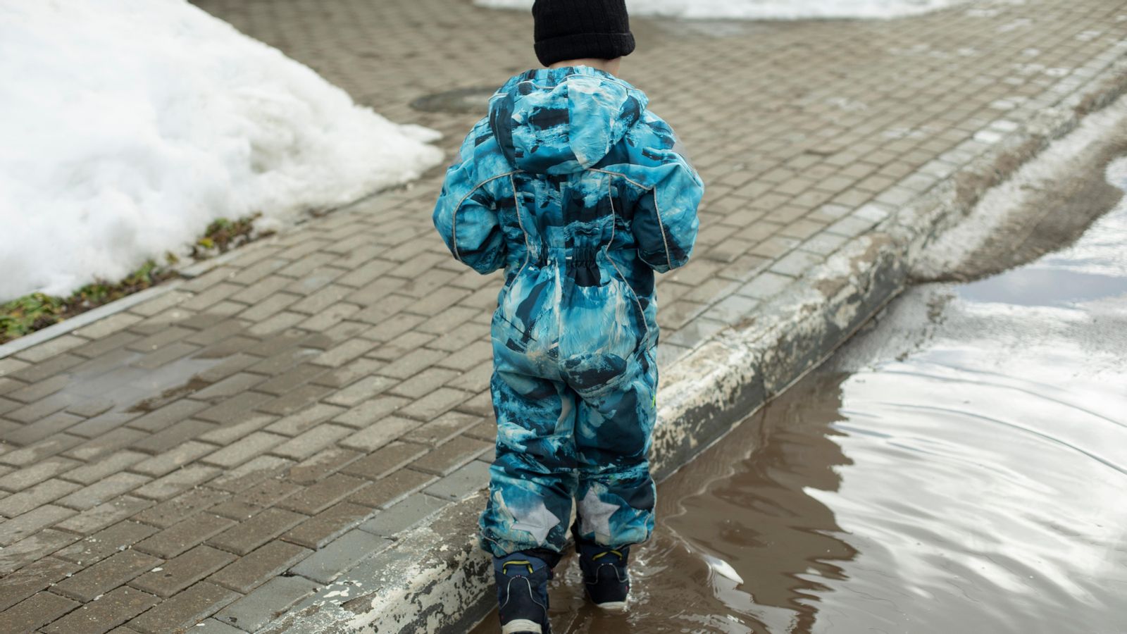 Un xiquet camina per un carrer amb neu