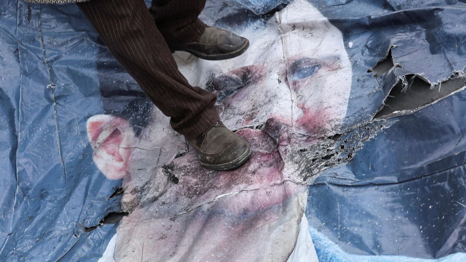 Un home xafa un cartell amb el rostre del president sirià Bashar Al-Assad a Damasc