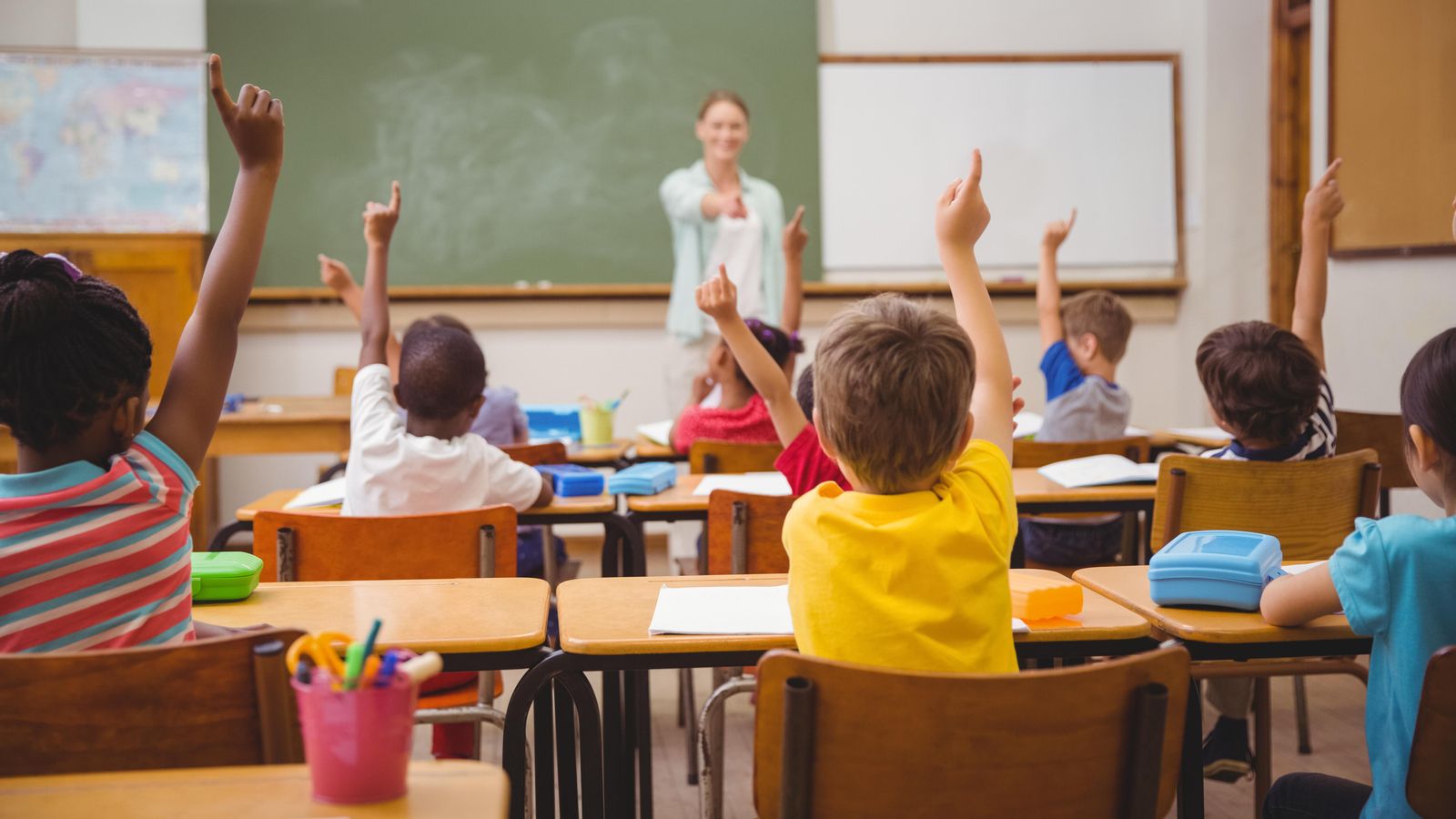 Un grup d'alumnes alçant la mà en una classe en una imatge d'arxiu