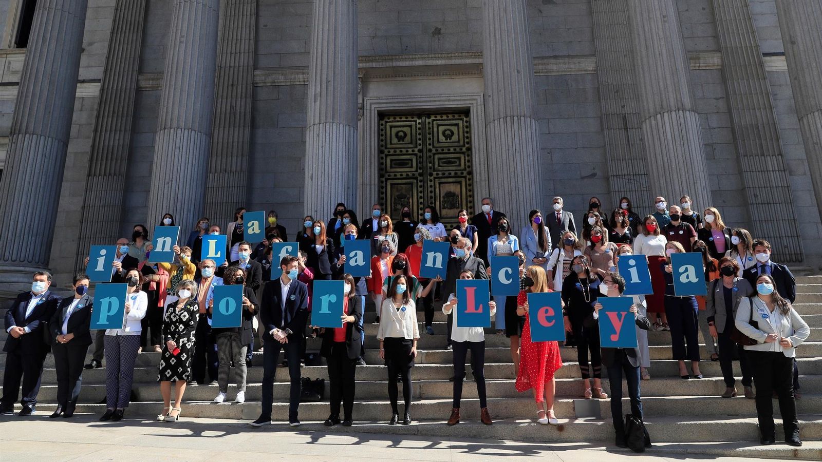 La ministra de Drets Socials, Ione Belarra, rodejada de diputats i diputades amb pancartes que composen el missatge "La infància per llei", a les portes del Congrés