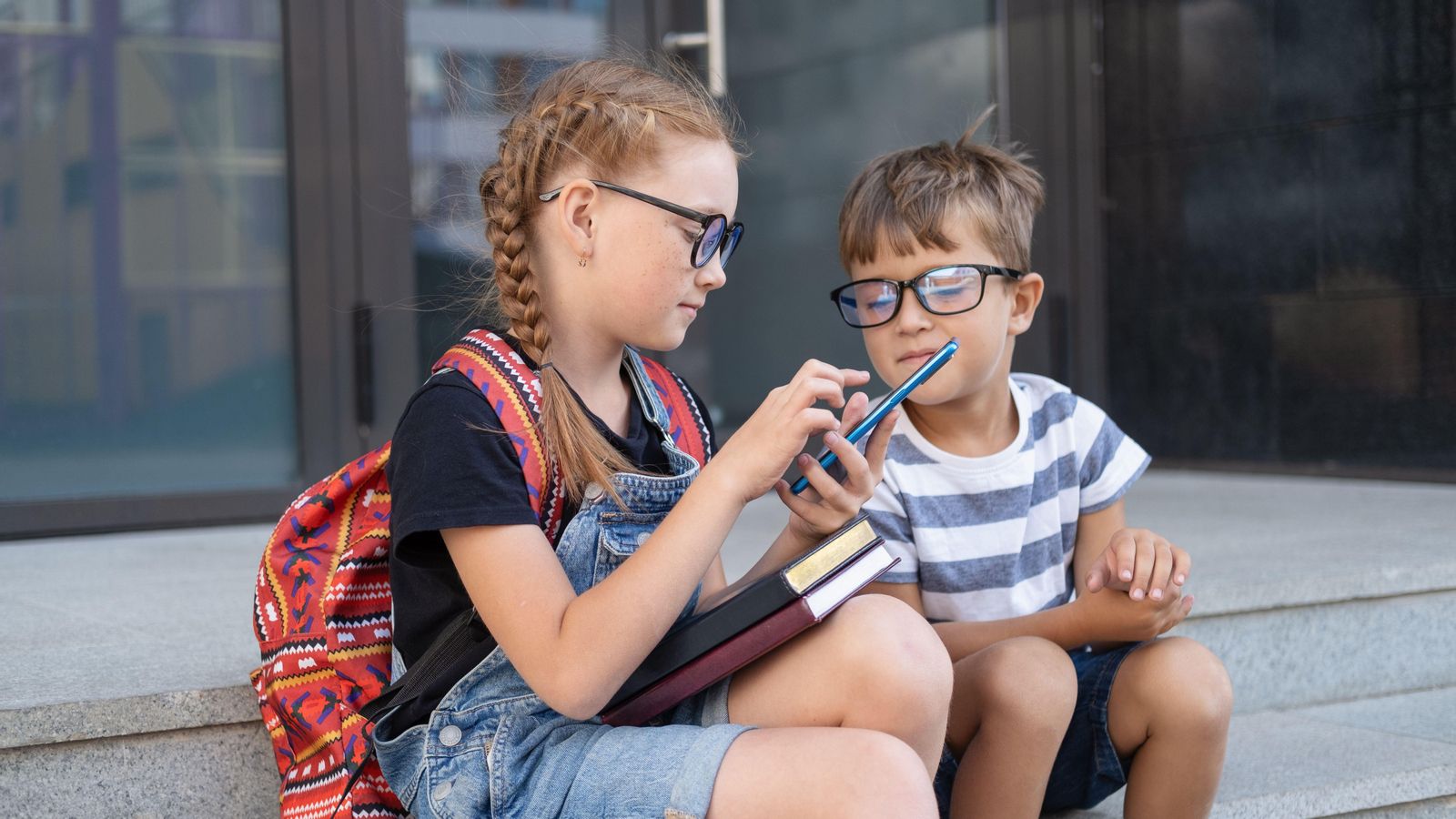 Dos xiquets amb ulleres miren el telèfon