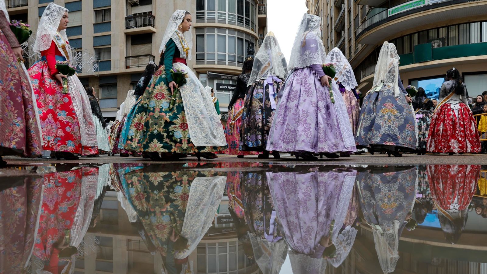 Un grup de dones s'obri pas cap a l'Ofrena sobre el carrer mullat de València