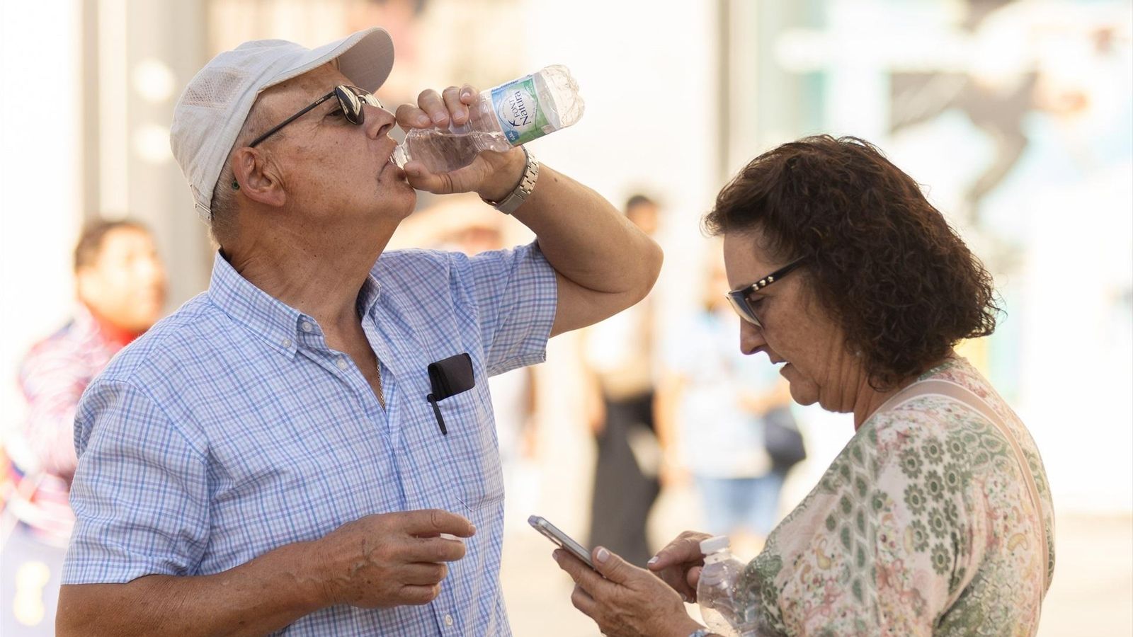 Un home beu aigua en plena onada de calor