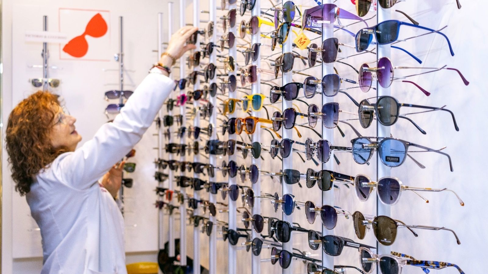Una dona ordena ulleres en un aparador d'una òptica