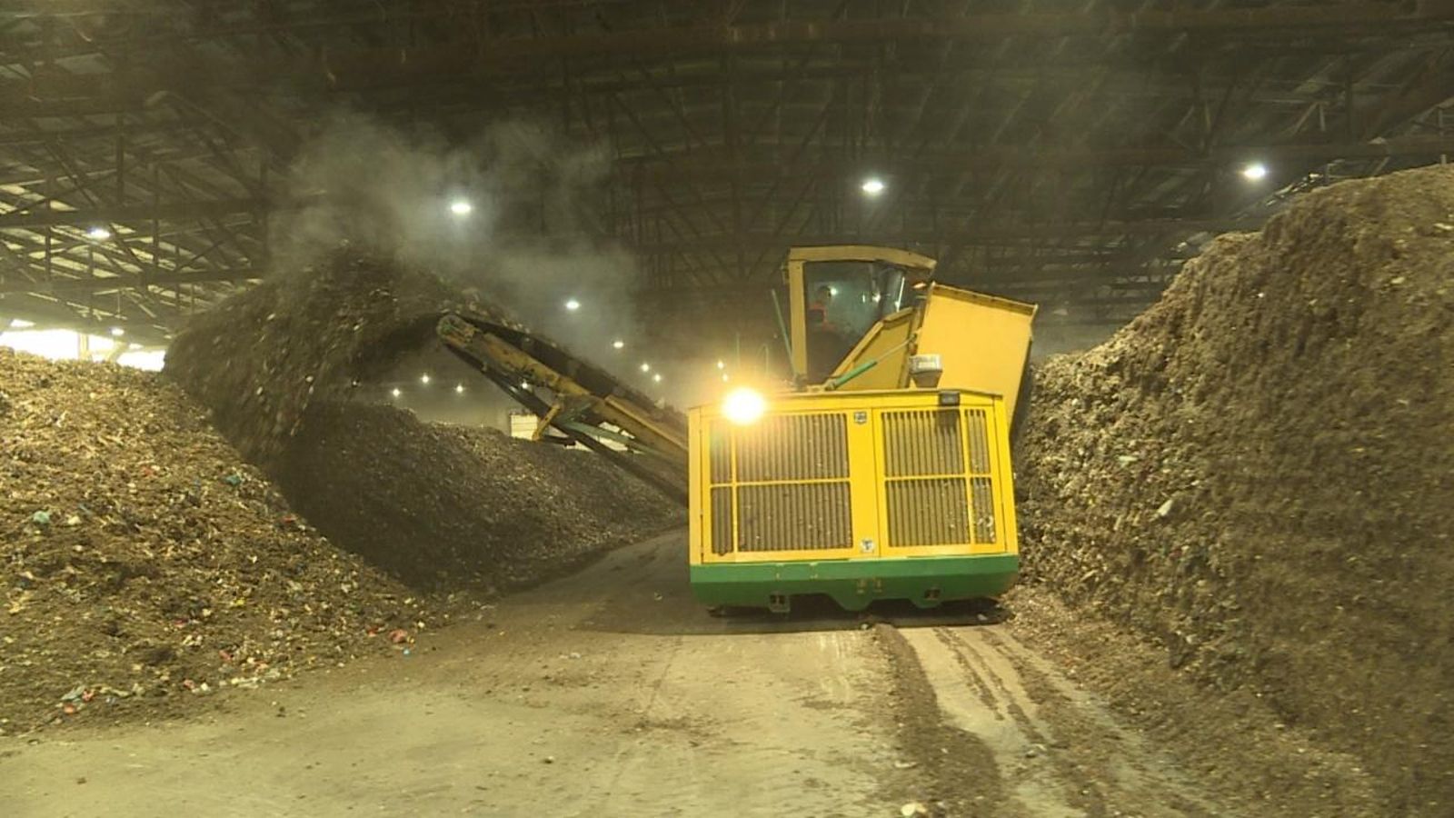 Una màquina expulsa les restes de material triturat en una planta de reciclatge