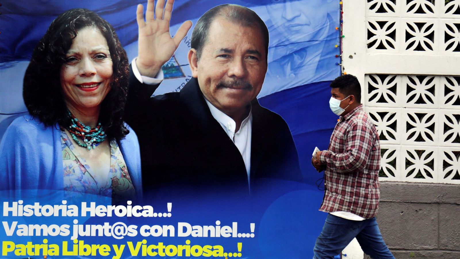 Un home passa per davant d'un cartell amb les candidatures de l'actual `president Daniel Ortega i la vicepresidenta Rosario Murillo