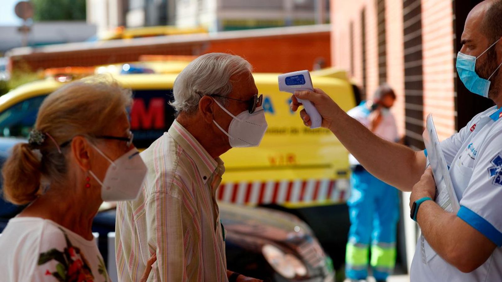 Un sanitari pren la temperatura a un home abans d'accedir a un centre de salut