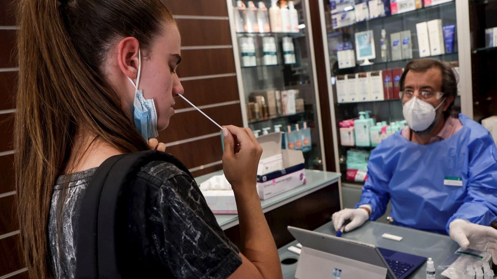 Una dona es fa un test d'antígens amb l'assessorament d'un farmacèutic