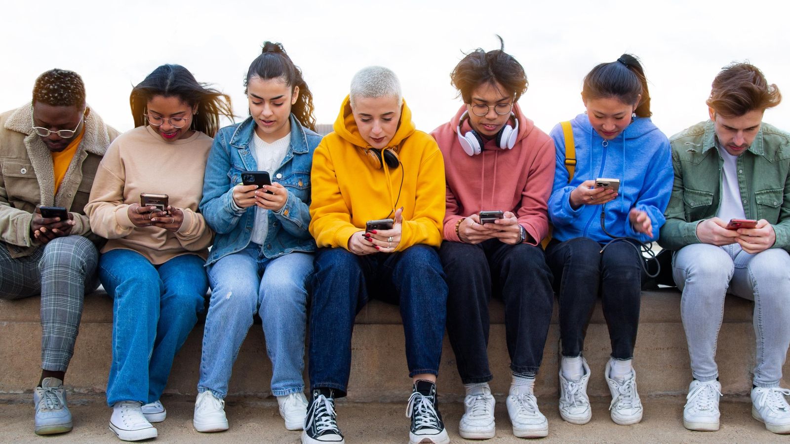 Grup de joves ignorant-se els uns als altres mirant els seus telèfons mòbils per a revisar les xarxes socials.