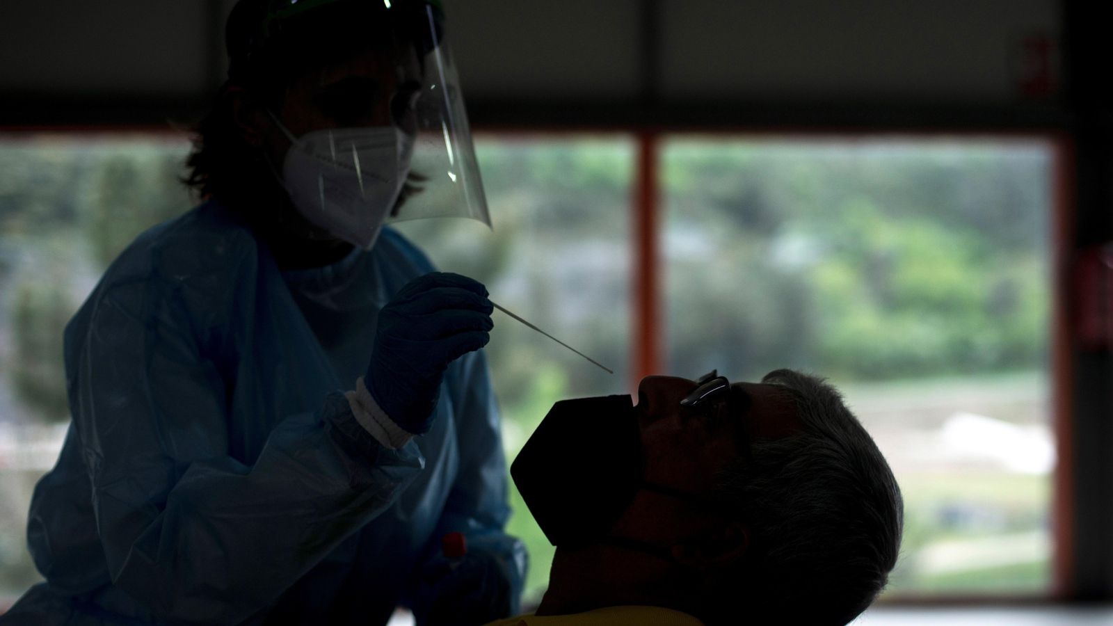 Una treballadora sanitària realitza una prova PCR a un home