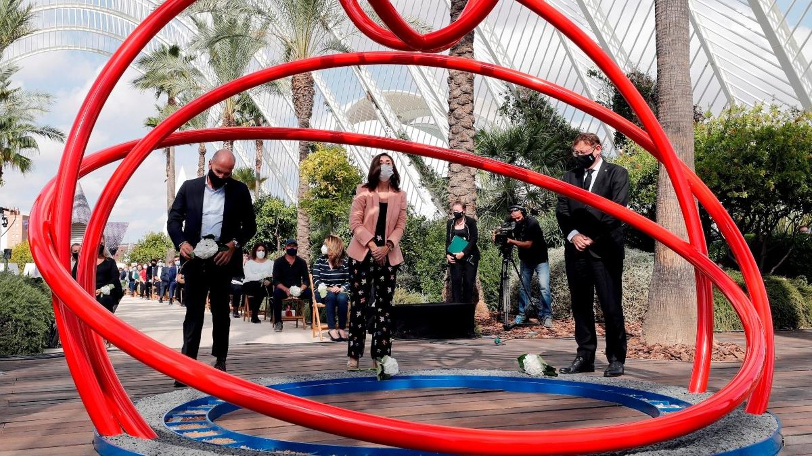 El president de la Generalitat, Ximo Puig, la metgessa, Esperanza Merino, i el periodista, Luis Motes, depositen flors en l'escultura en memòria de les víctimes de la covid-19