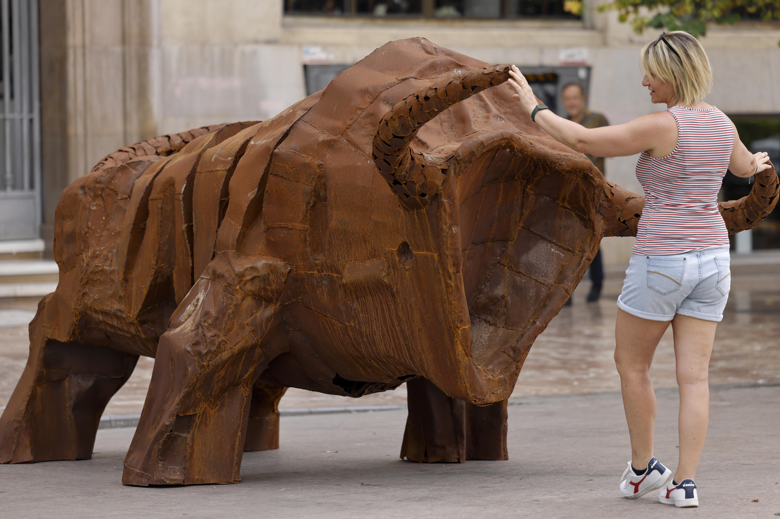 Una dona interactua amb l'escultura ‘El toro’, de Ripollés