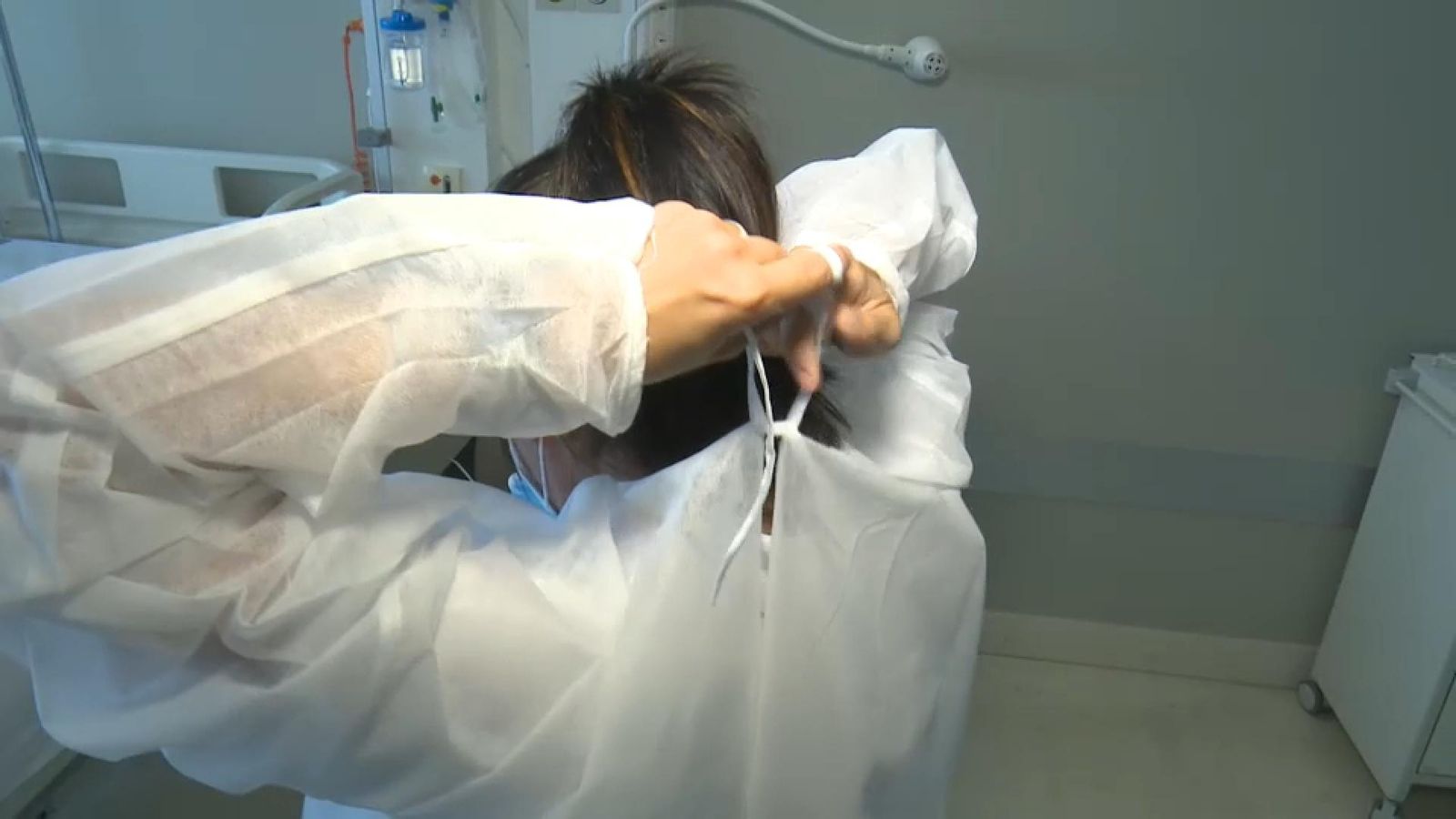 Una sanitària es lleva una bata d'un sol ús
