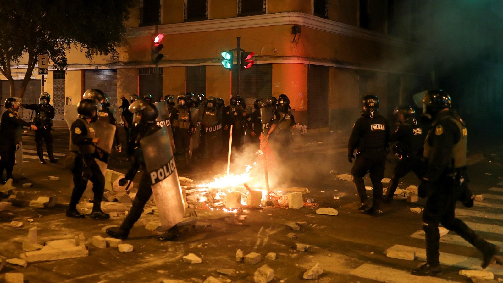 Agents de Policia tracten d'apagar una foguera en el carrer durant les protestes contra Boluarte, a Lima