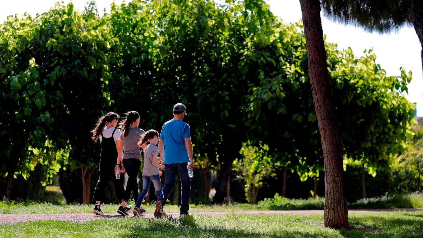 Un home passeja amb tres xiquetes per l’antic llit del Túria a València ahir dilluns